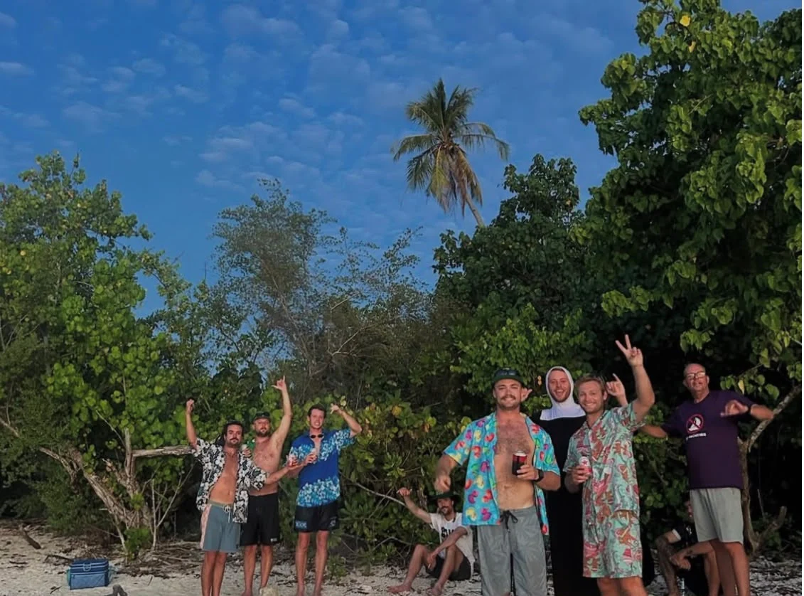 Charter guests celebrating together on a palm-lined island