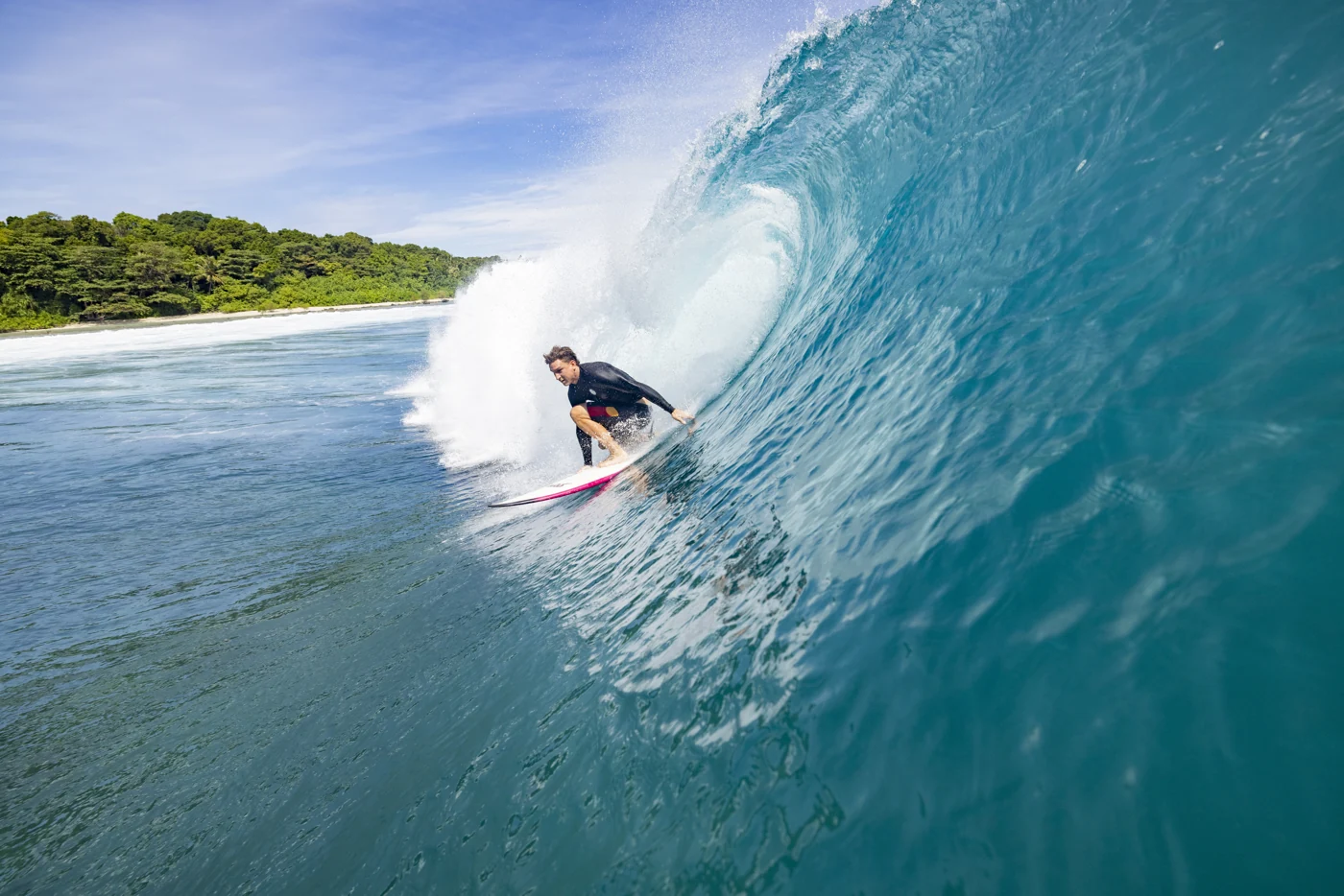 A surfer emerging from a turquoise Mentawai barrel